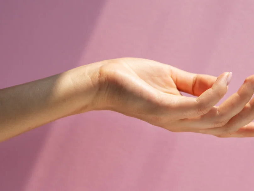 A hand extends forward, poised to touch a surface, with a focus on the smoothness enhanced by hand cream.