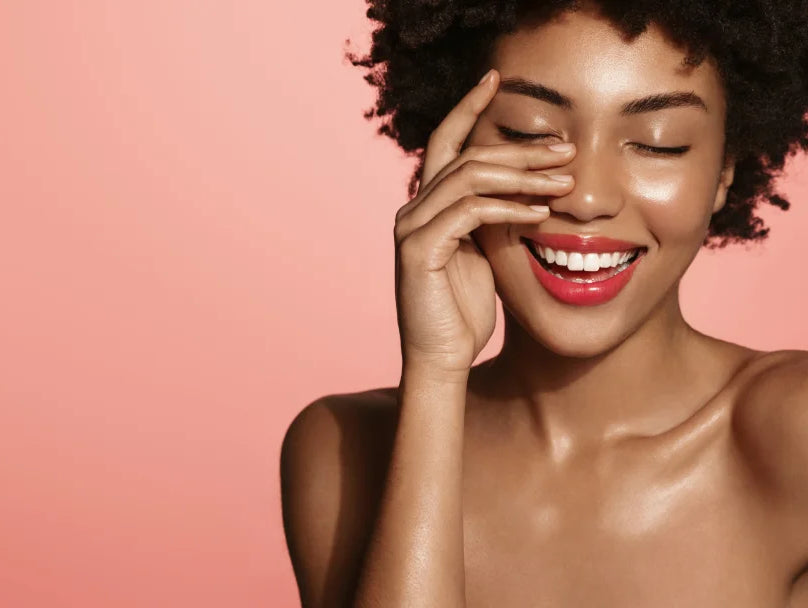 woman smiling with eyes closed on a pink background
