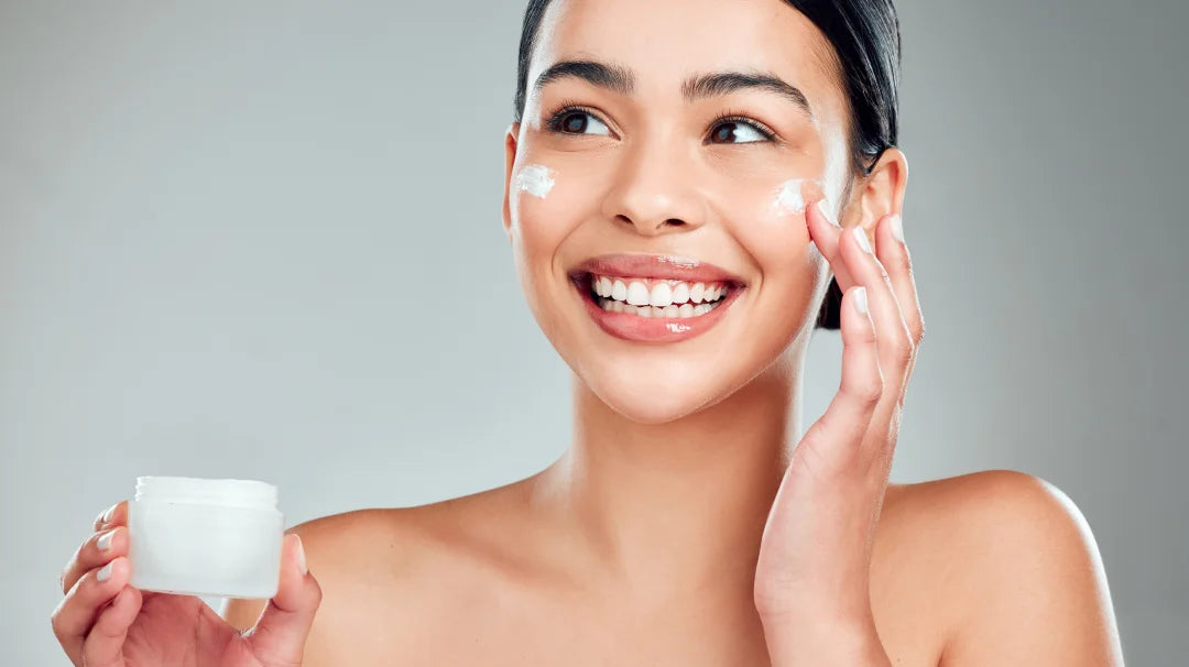 A woman applying face cream from a jar, showcasing a skincare routine focused on hydration and nourishment.