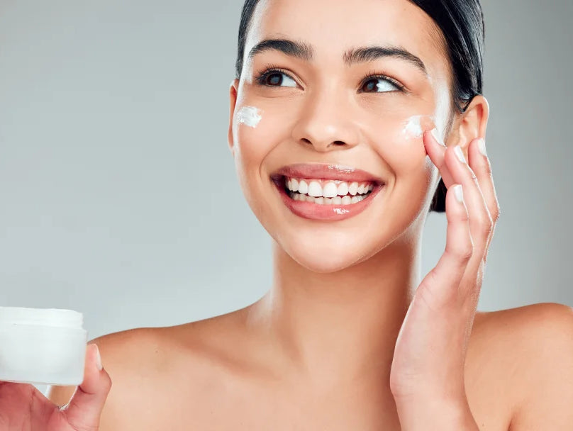 A woman applying face cream from a jar, showcasing a skincare routine focused on hydration and nourishment.
