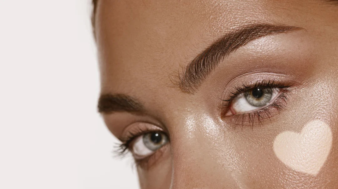 A woman showcasing heart-shaped makeup on her face, radiating confidence with a sun-kissed self-tanning glow.