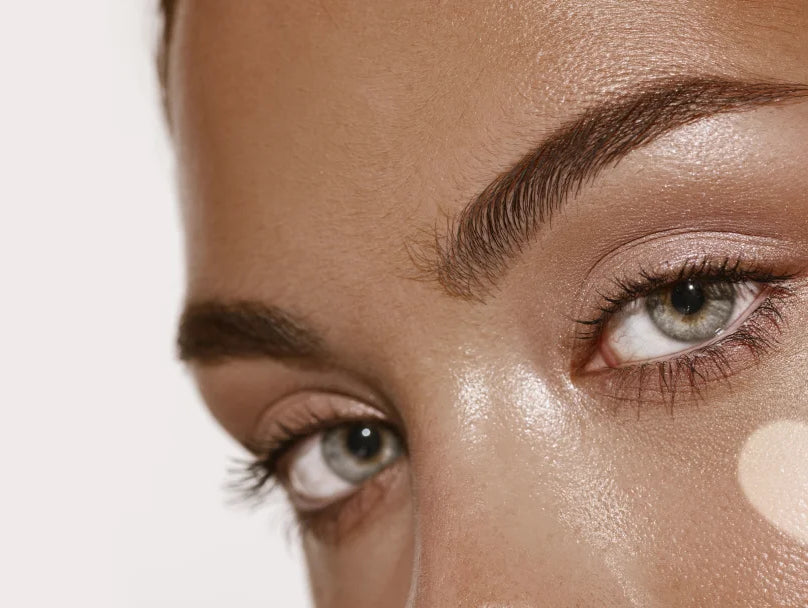 A woman showcasing heart-shaped makeup on her face, radiating confidence with a sun-kissed self-tanning glow.