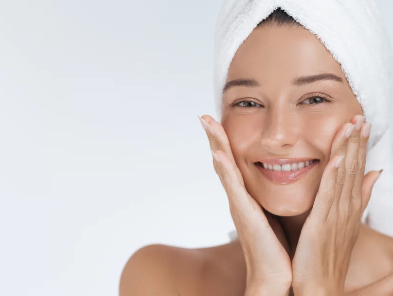 A smiling woman with a towel on her head, showcasing the benefits of Hyaluronic Acid Cream for radiant skin.