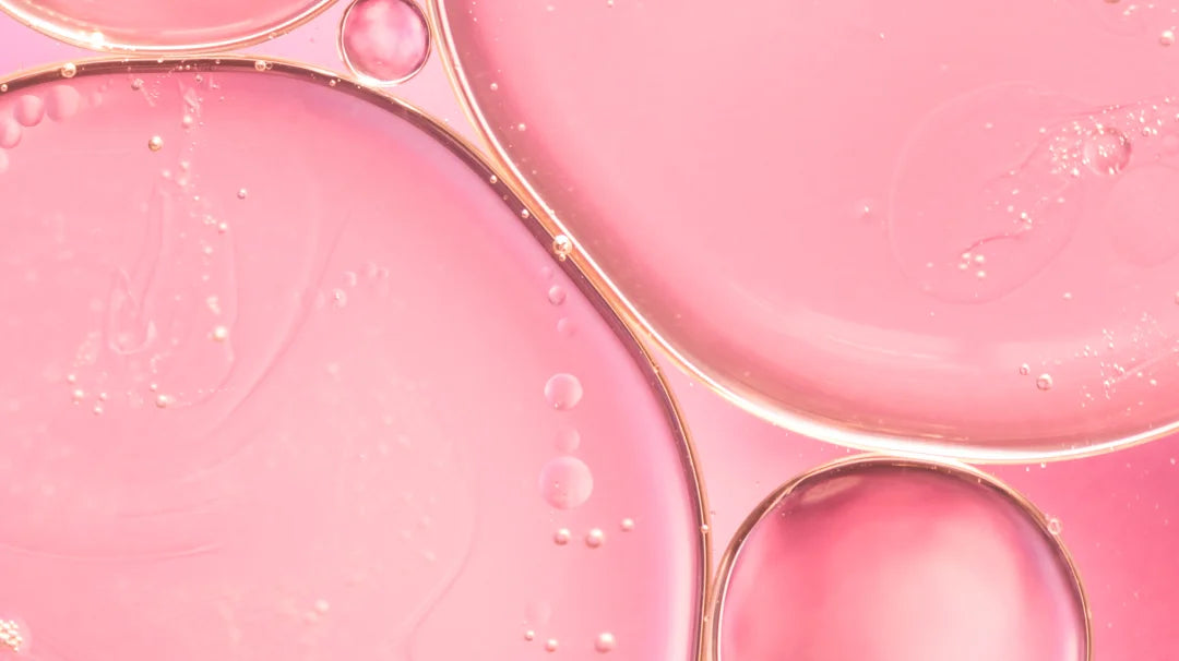 Oil drops on a pink background, symbolizing a product that stimulates collagen production for skin health.
