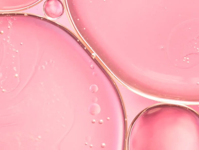 Oil drops on a pink background, symbolizing a product that stimulates collagen production for skin health.